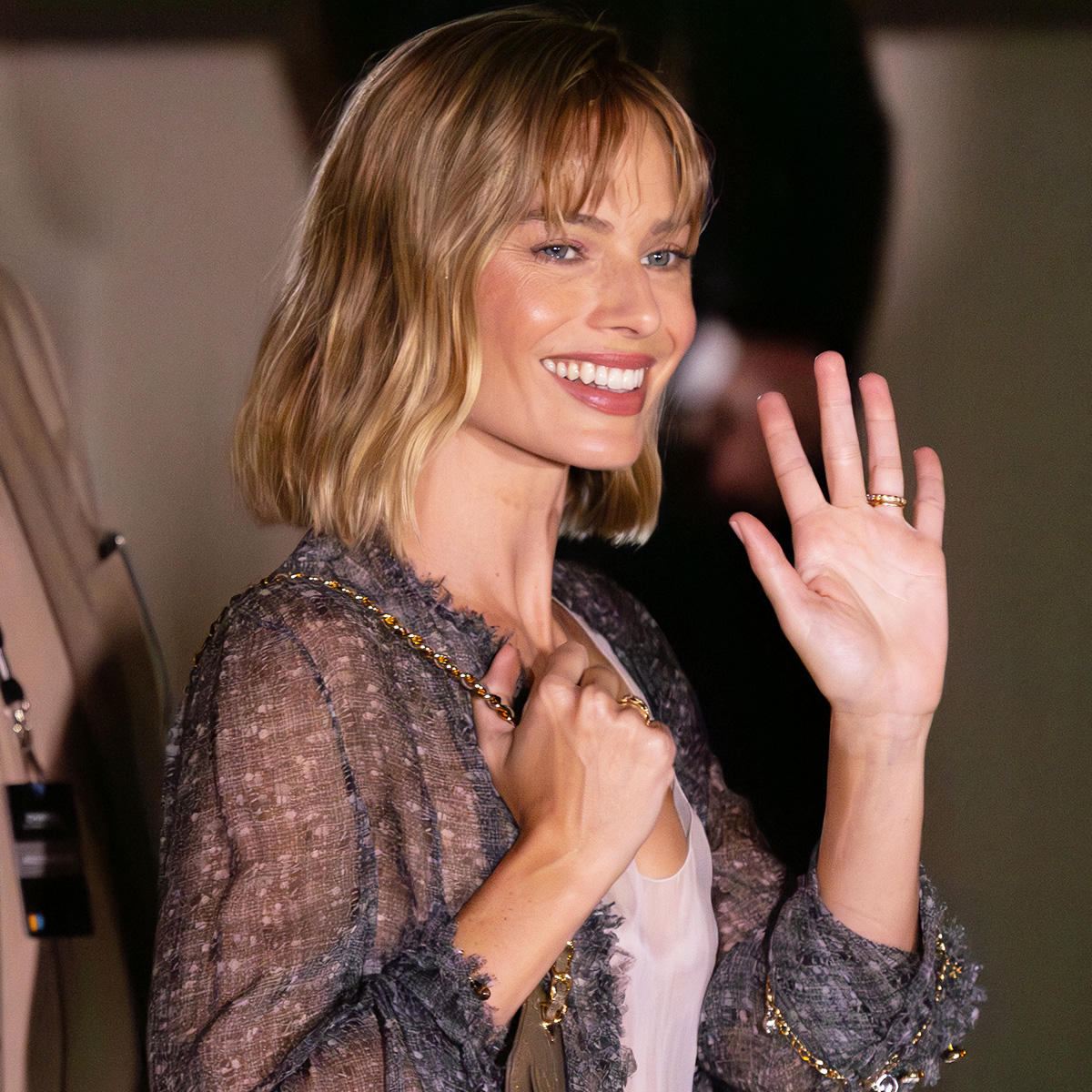 Margot Robbie attending the Chanel F/W 26 show during PFW, wearing a sheer jacket, tank, and pants with pumps and a Chanel 25 mini bag