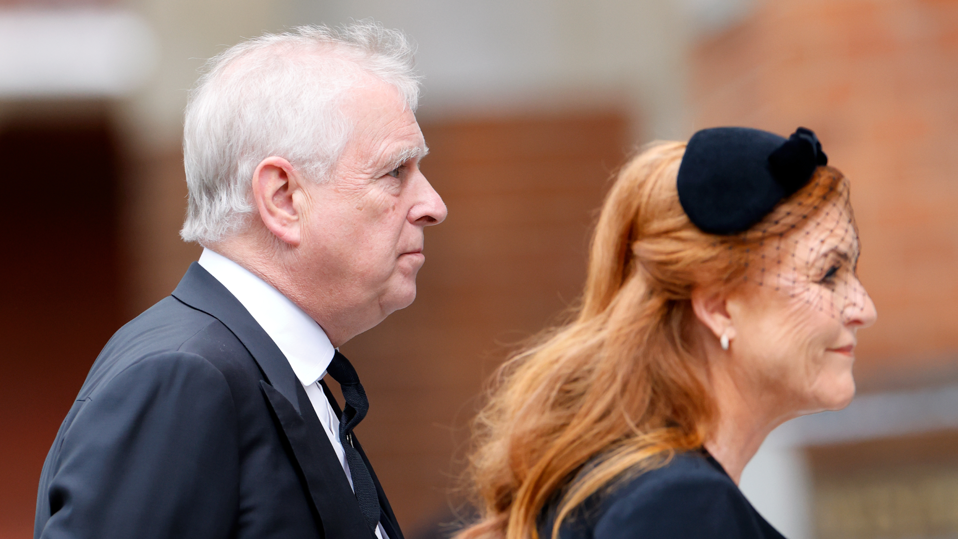 Prince Andrew walking behind Sarah Ferguson wearing black outfits
