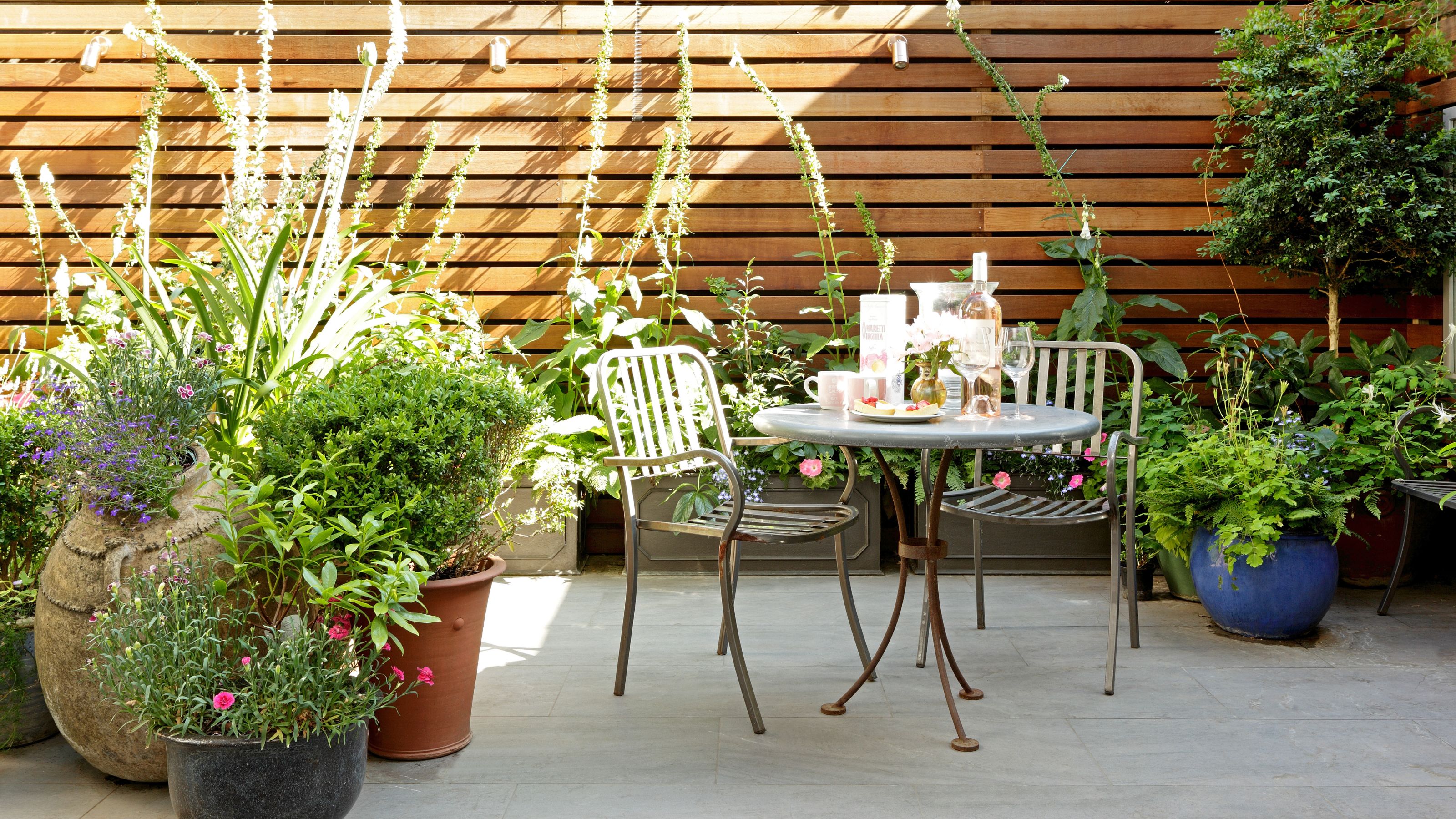 patio with table and chairs and planters