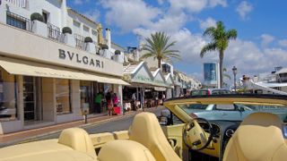 A luxury car and shops by the Puerto Banus harbour