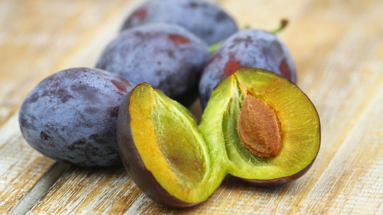 Plums on a board with one cut open 