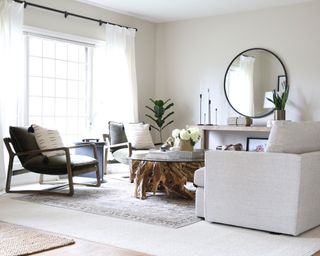 Large round mirror in neutral living room scheme, with unique tree root coffee table.