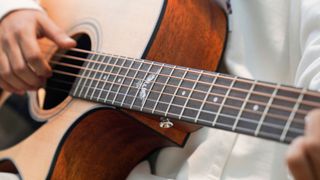 Closeup of hands playing a Kepma Fenix Series acoustic guitar