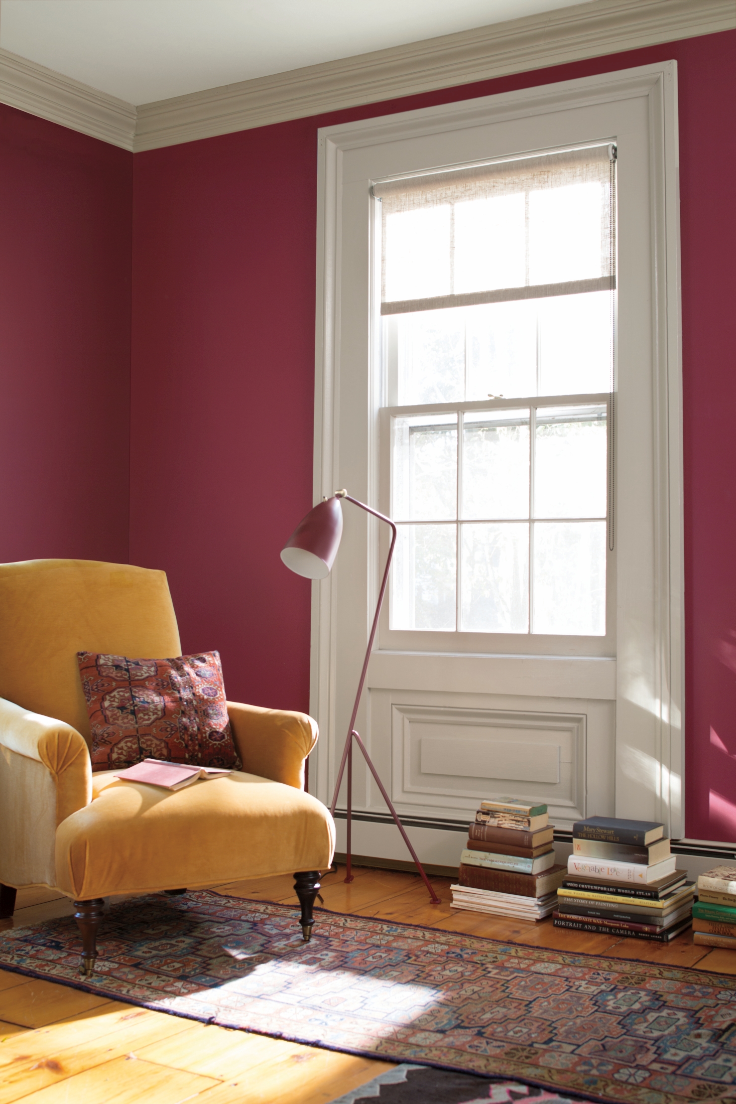 Red living room with red wall, yellow armchair, wood floor and patterned rug