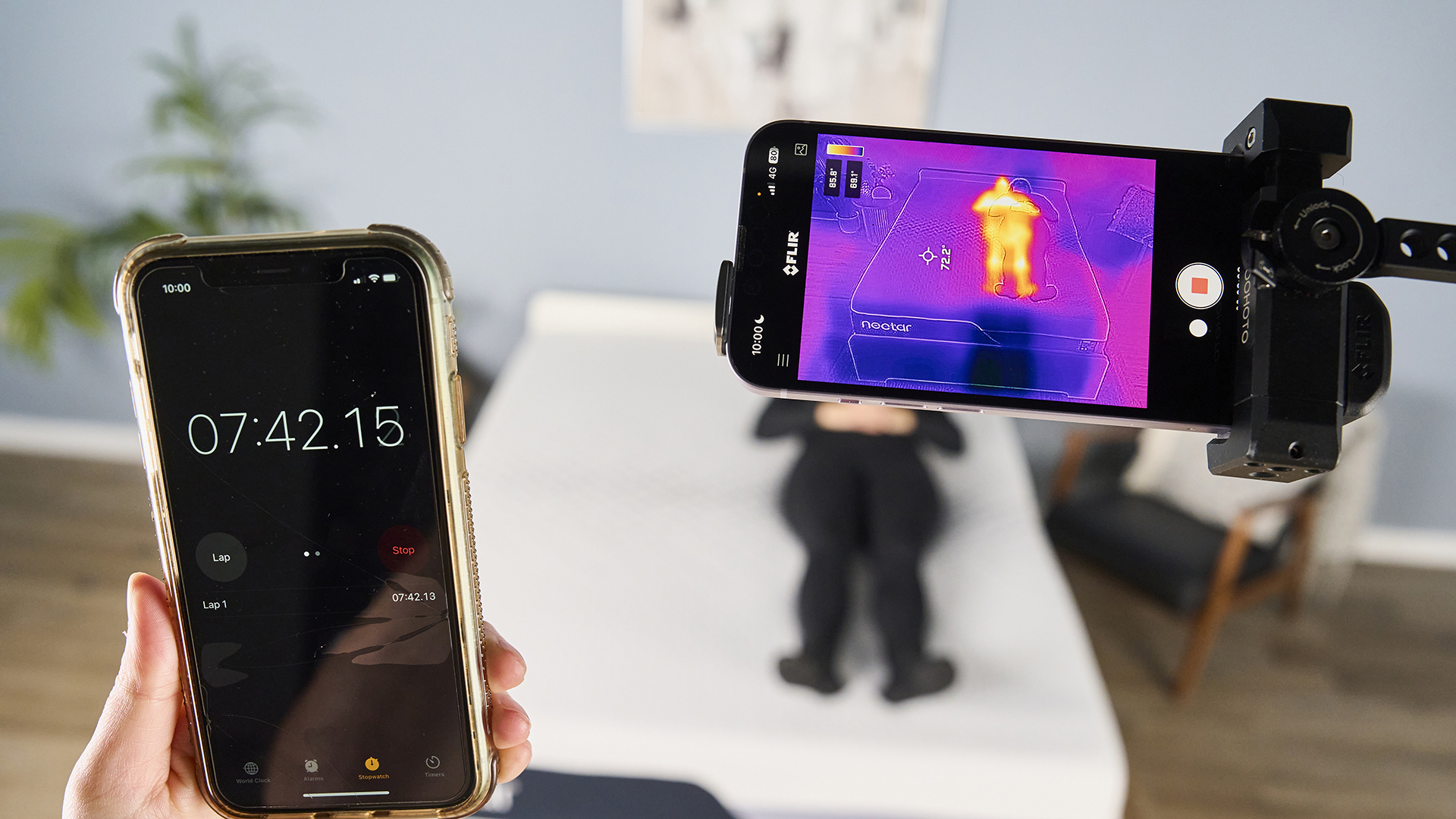 This image is a behind the scenes of our thermal imaging objective testing. In the background, our tester Lauren Jeffries lies on the Nectar Premier Memory Foam Mattress in our sleep studio. In the foreground, a phone displaying a thermal imaging camera records how Lauren is much warmer than the surface of the mattress. To the left, another phone displays a stopwatch indicating this is minute 7 of the test