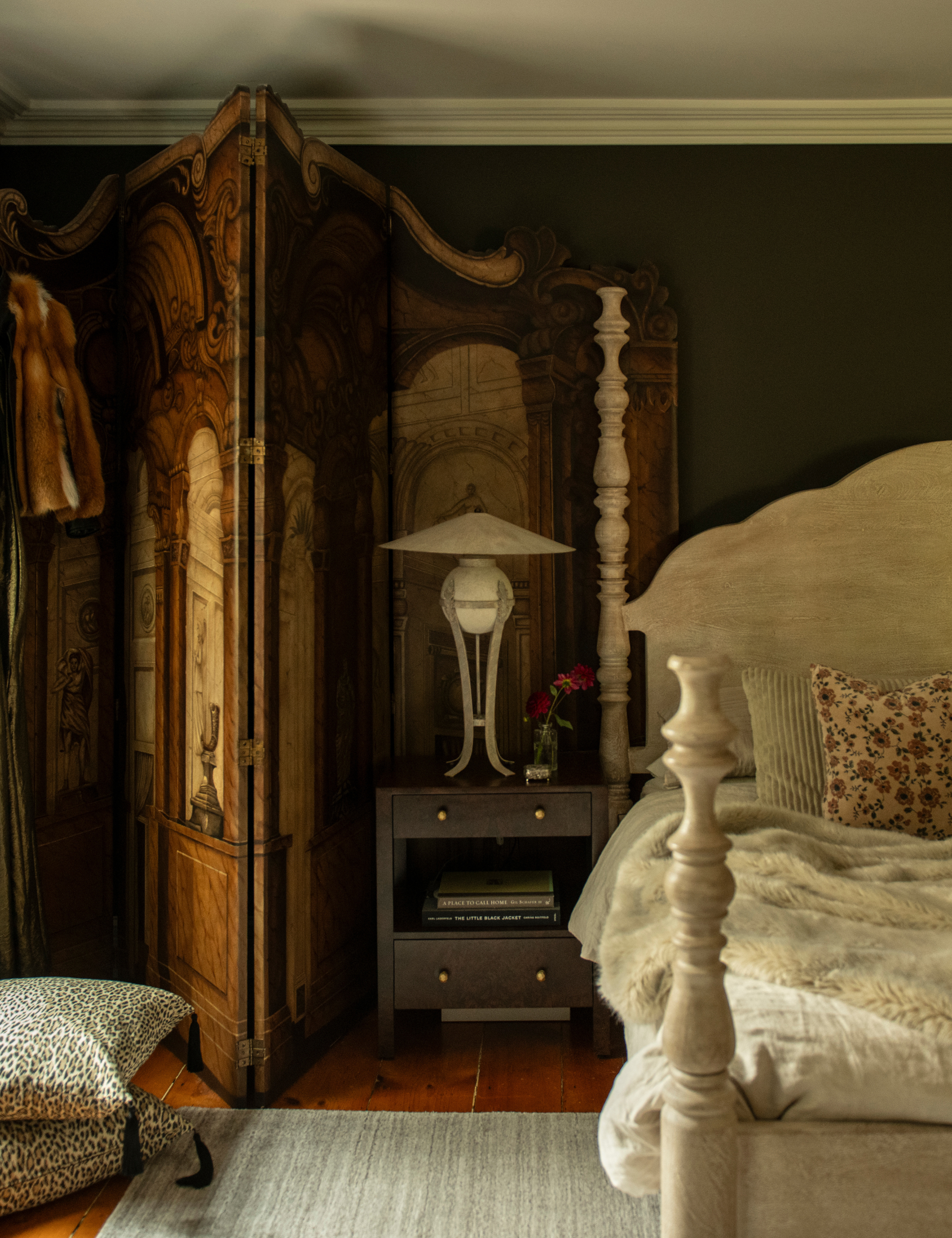 Nicole Fisher-designed bedroom featuring la four-post bed frame, layered furs, tasseled pillows, and an antique wooden room divider