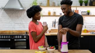 Two people making a protein shake in a blender