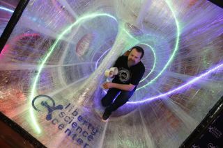 Eric Lennartson poses inside one half of the completed Tape Wormhole before it was opened to the public.