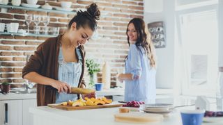Caucasian women chopping fruit in kitchen
