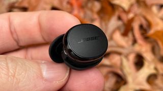 Bose QuietComfort Earbuds wireless earbuds single bud held in hand showing outside of bud and Bose logo