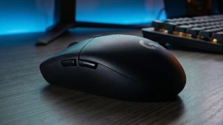 Logitech G305 LIGHTSPEED gaming mouse on a desk with keyboard and monitor stand