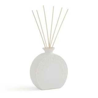 White shell-like diffuser bottle with diffuser reeds coming out of it