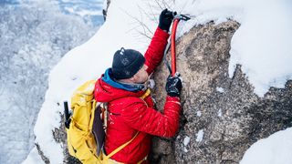 how to use an ice axe: mountaineer using pick to hook around a rock