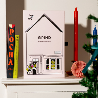 Grind advent calendar on a bookshelf wiht two books and a candle