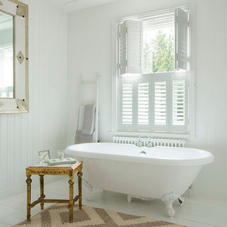 bathroom with bright white walls white bathtub and white window