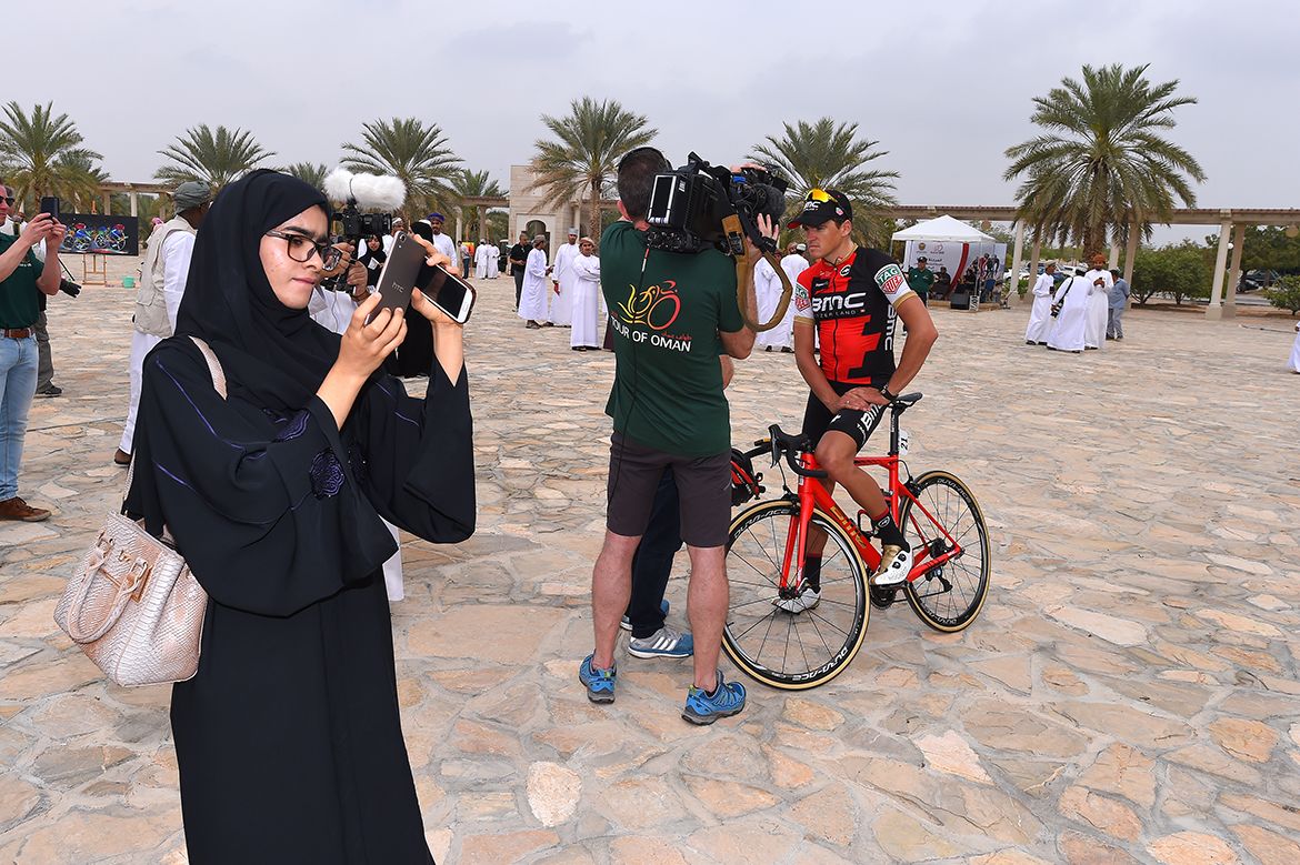 Greg Van Avermaet talks to television as one fan checks out her photos
