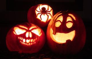 Three carved pumpkins lit up at night