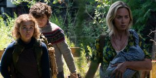 Millicent Simmonds, Noah Jupe, and Emily Blunt walking through the woods in A Quiet Place Part II.