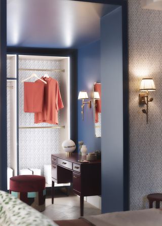 walk in closet/wardrobe with illuminated hanging space, blue walls and gold fixtures and fittings