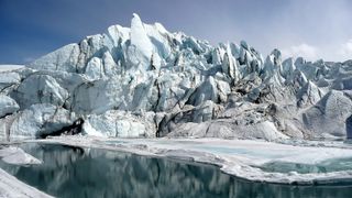 Spiked peaks of ice come together to create a large glacier floating on the surface of still, icy water