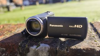 The Panasonic HC-V180 camcorder on a brick wall in the sun