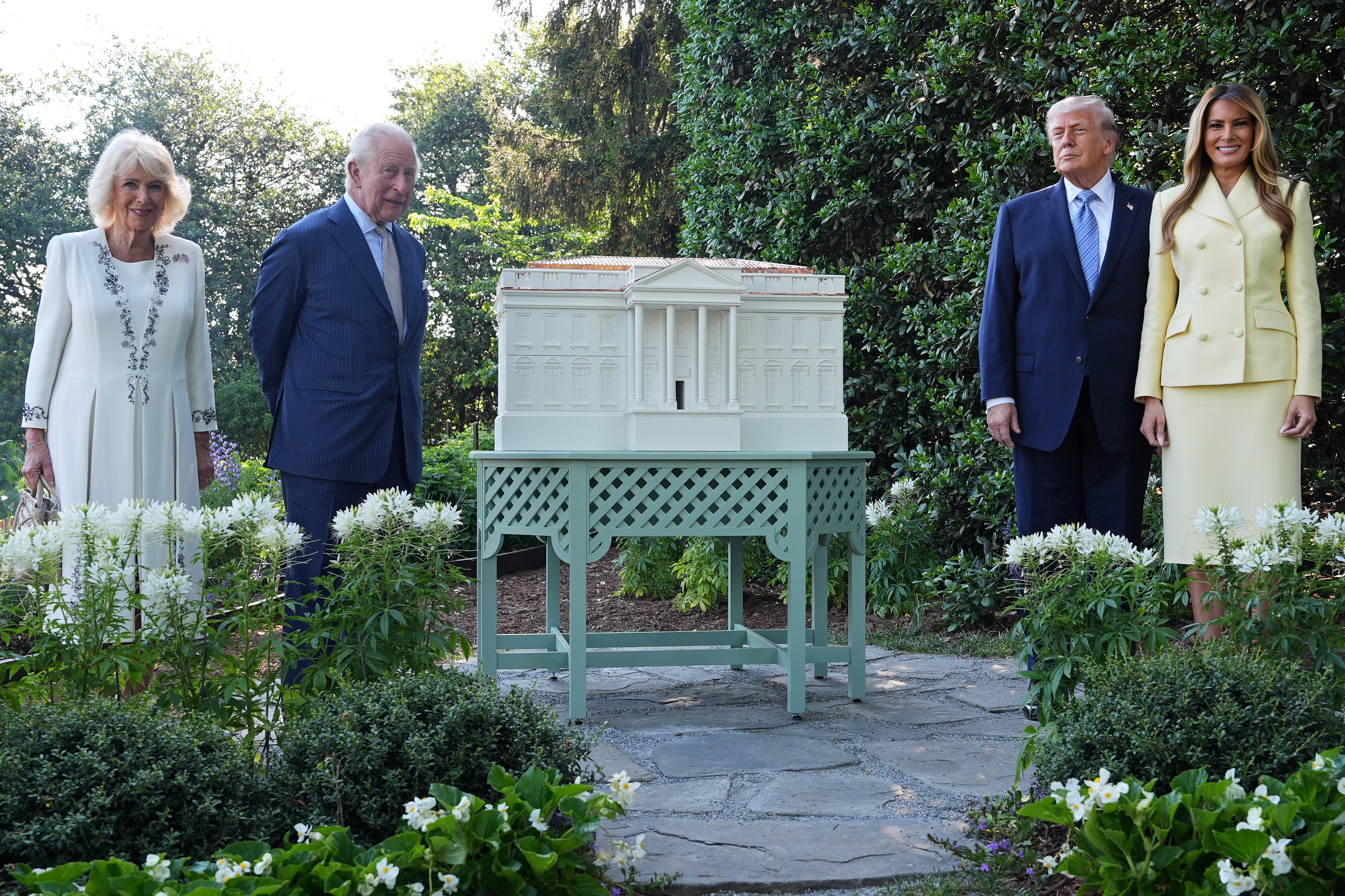 Queen Camilla and King Charles standing with Donald and Melania Trump next to a beehive