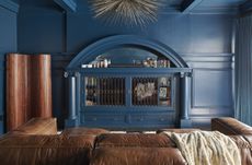 A living room with a brown couch and blue walls