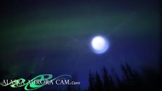 An image of the spinning orb of blue light moving across an aroura-filled sky in Alaska.