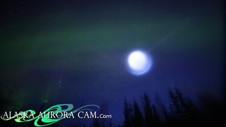 An image of the spinning orb of blue light moving across an aroura-filled sky in Alaska.