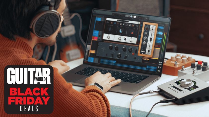 A man uses a MacBook with Universal Audio plugins on the screen, an audio interface, and guitar pedals in the background