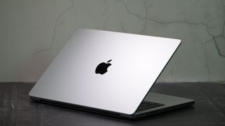 MacBook Pro 14-tum (2023) i en studio med locket delvis stängt som visar Apples logotyp