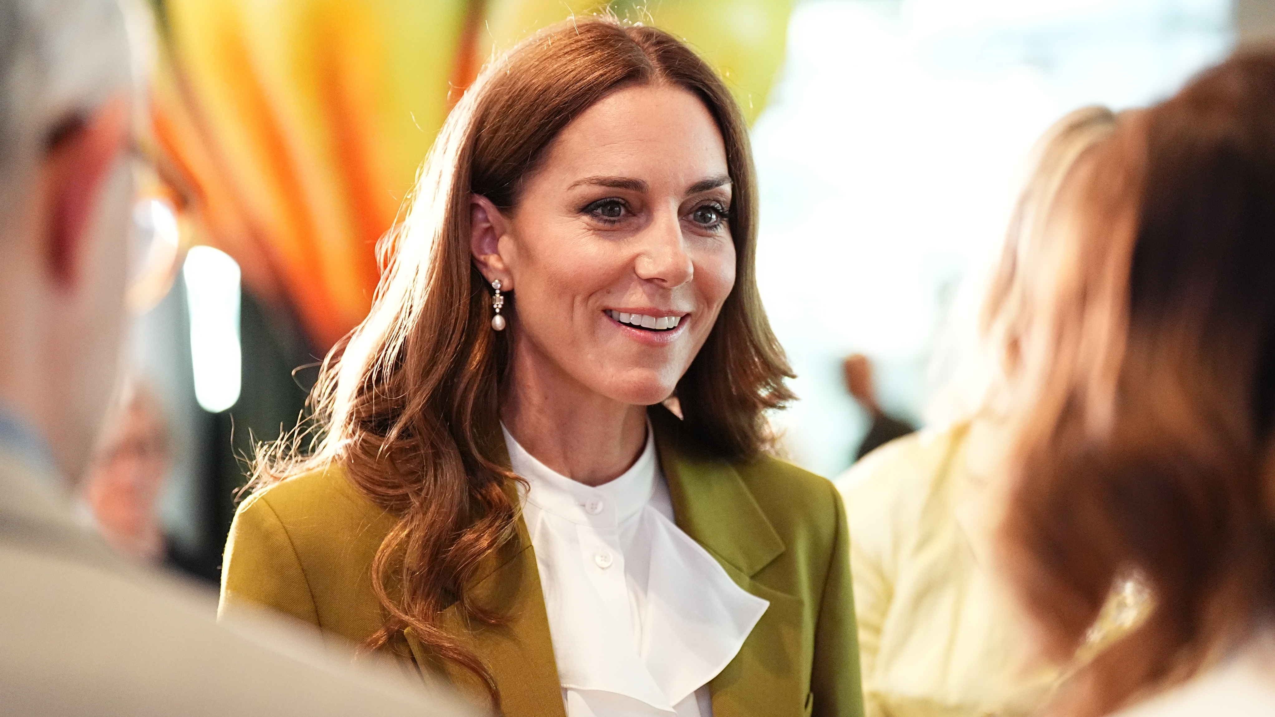 Catherine, Princess of Wales smiles, wearing an olive green suit, at the British Fashion Council at 180 Studios in central London