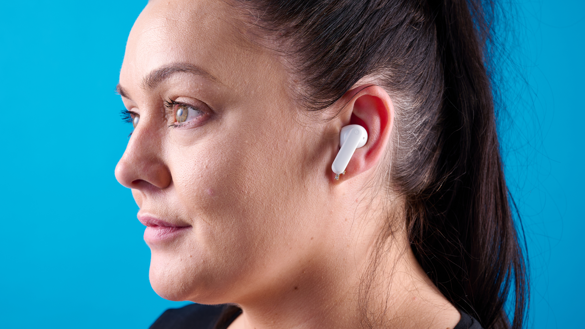 CMF Buds 2 Plus in light gray photographed in front of a blue background