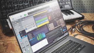 Apple Logic Pro DAW running on a MacBook with a synthesizer in the background