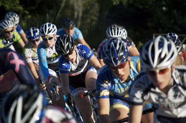 The women's peloton flies through a corner.