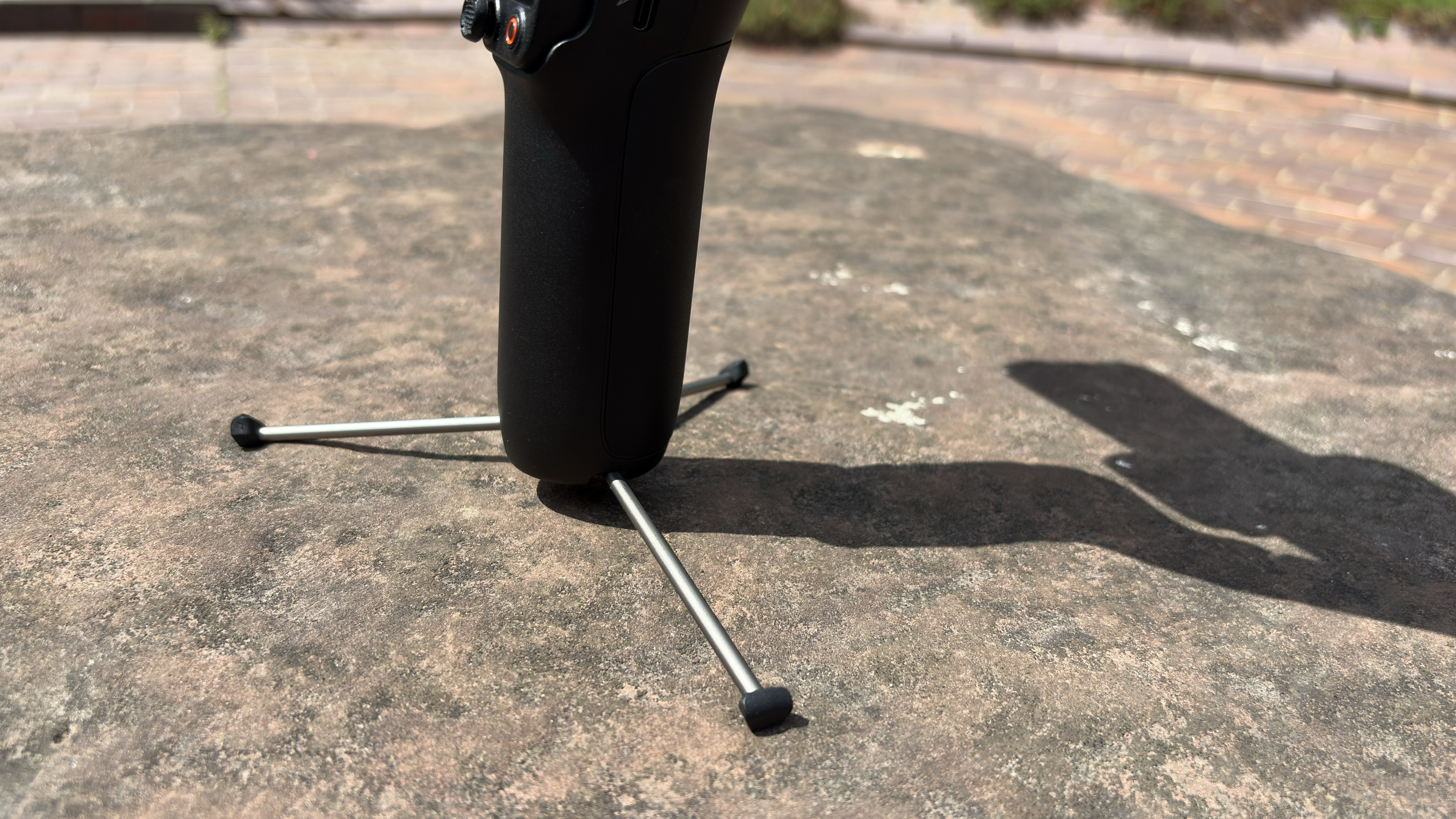 Shot of the lower end of the gimbal with three spindly metal tripod legs deployed so that it can stand on a surface.