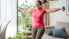 woman uses dumbbells to exercise at home