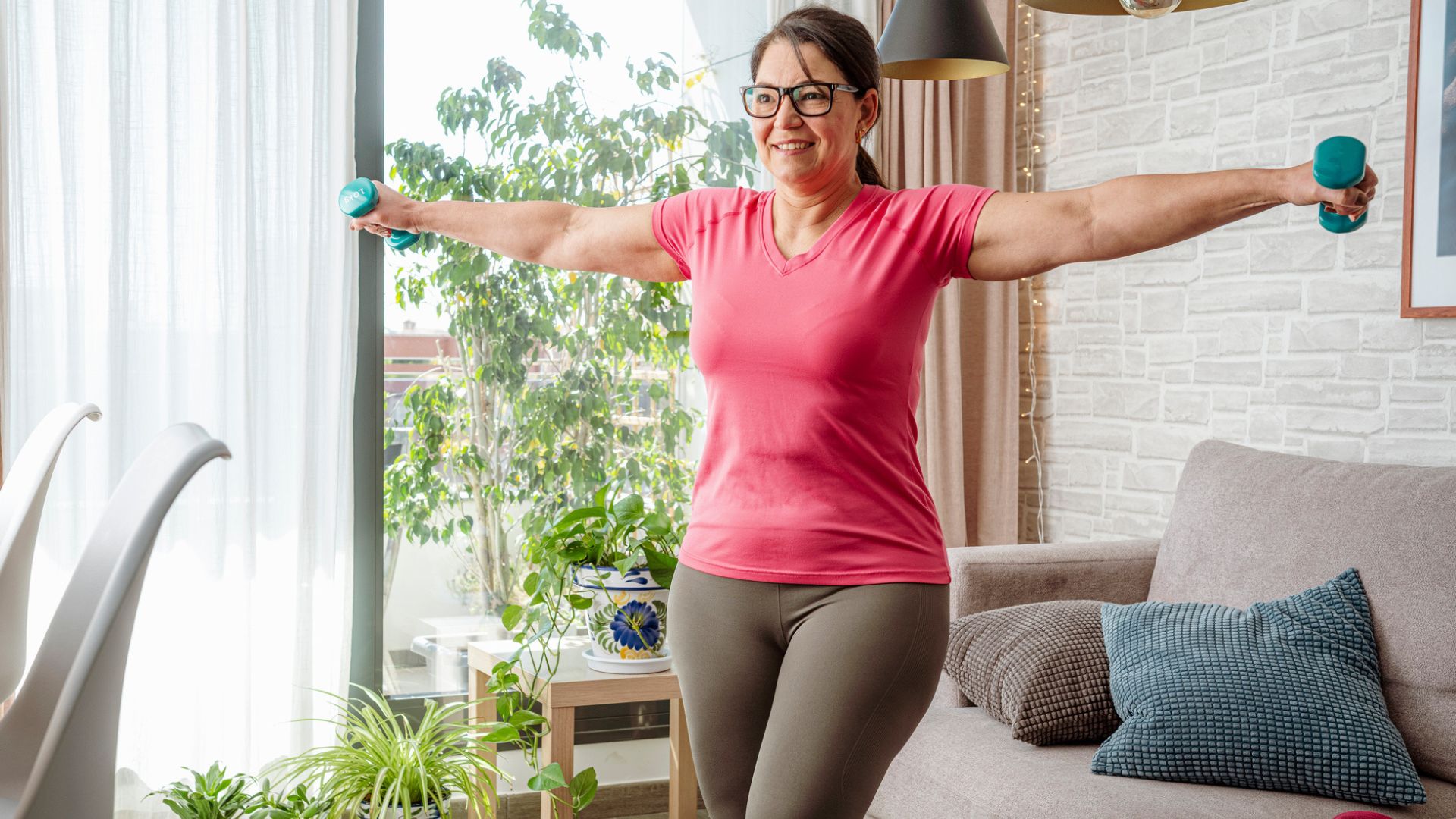 woman uses dumbbells to exercise at home 