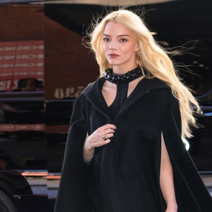 Anya Taylor Joy with her blonde hair pulled into an updo hairstyle. She's wearing a strapless white dress and a necklace. 