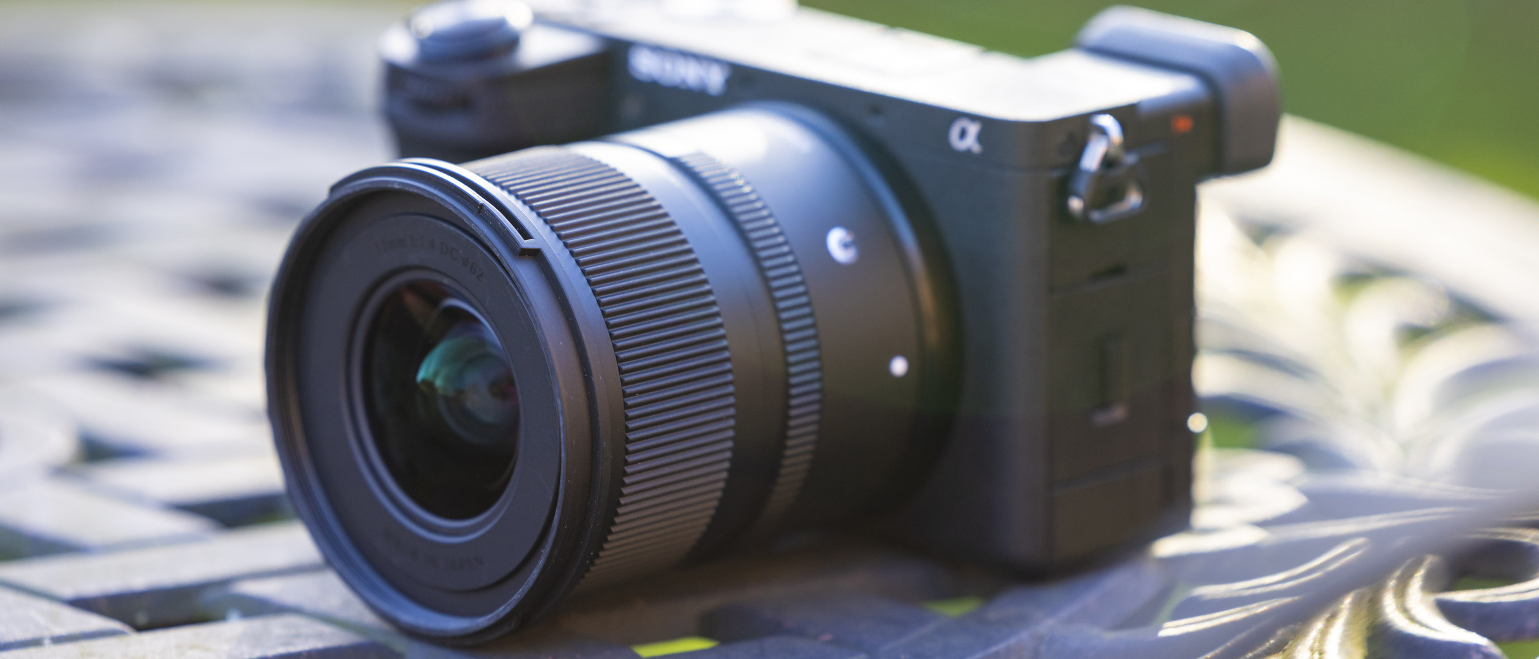 Sigma 12mm f/1.4 lens attached to a Sony A6700 camera, on a metal garden table