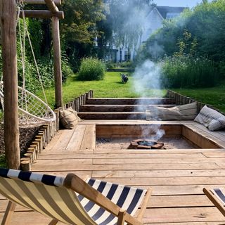 outdoor fireplace in a wood decking with black and white deckchairs