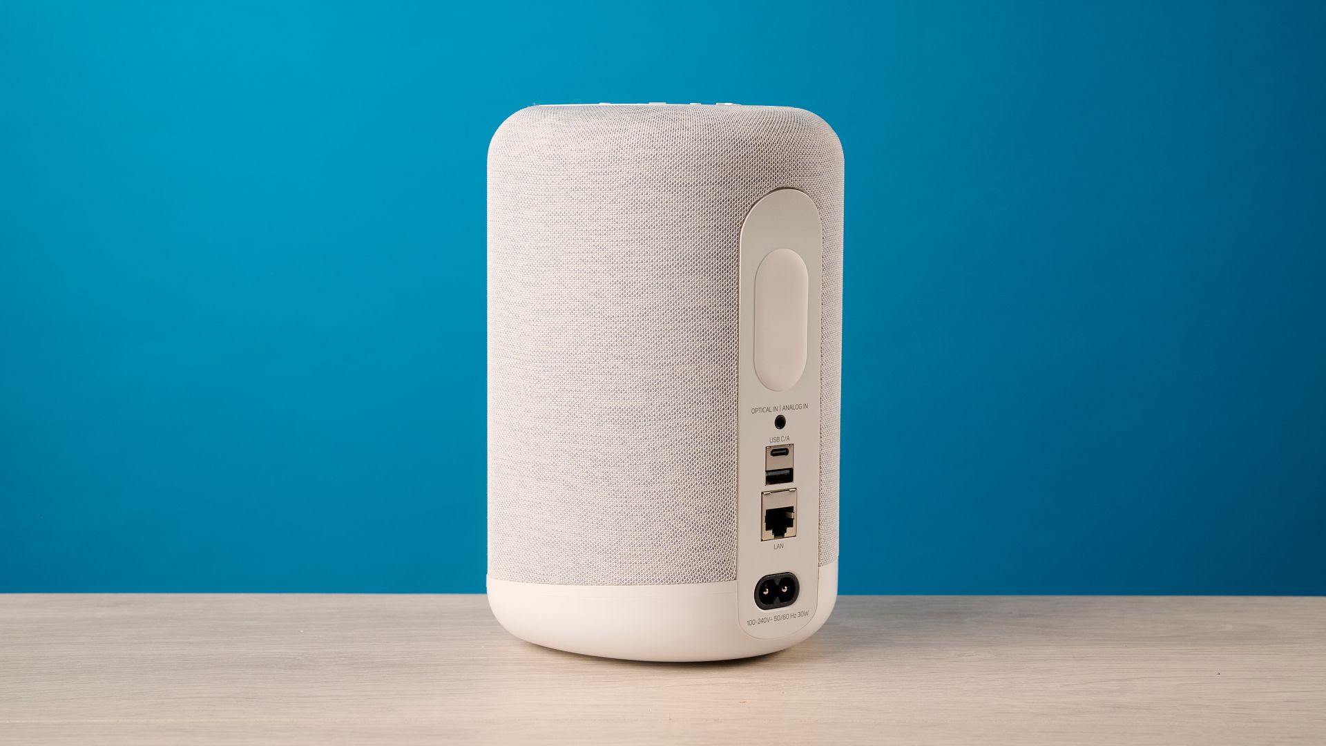 the bluesound pulse flex wi-fi speaker in pale gray photographed against the blue tom's guide background