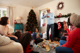 Multigenerational family playing a game of charades in Christmas living room