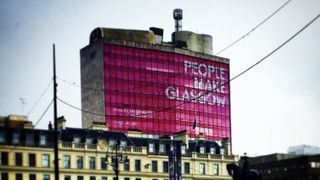A view of a building in Glasgow city centre with a large banner on the side with the words 'People Make Glasgow'