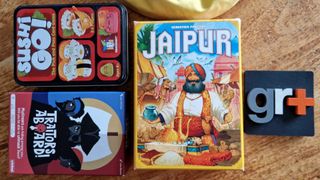 Traitors Aboard, Sushi Go, Jaipur, and Bananagrams on a wooden table beside a GR+ logo