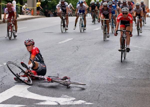 Another rider slides on the rain-slicked road, while others unclip to prevent from doing the same.