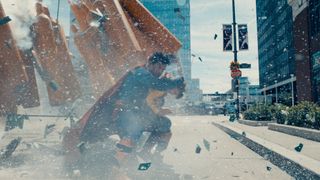 David Corenswet as Superman protecting a child from debris in Superman
