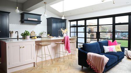 Kitchen-diner with herringbone floor, Crittall-style doors, dark blue Shaker-style kitchen with light pink island, and blue velvet sofa