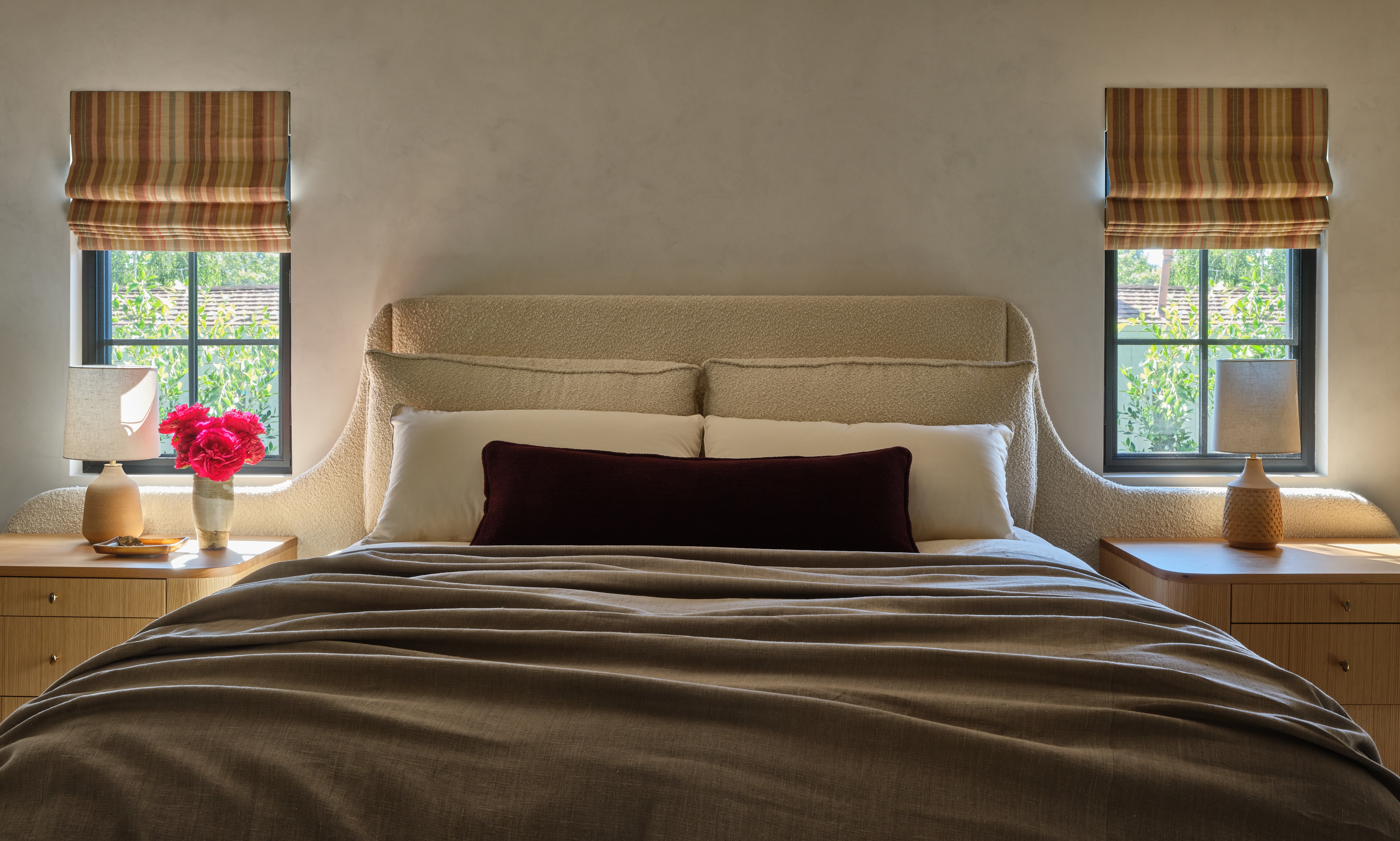 A contemporary bedroom with a symmetrical layout featuring matching nightstands positioned directly above windows at either side of the bed