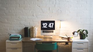 Office desk with a laptop, lamp, plant and personal items